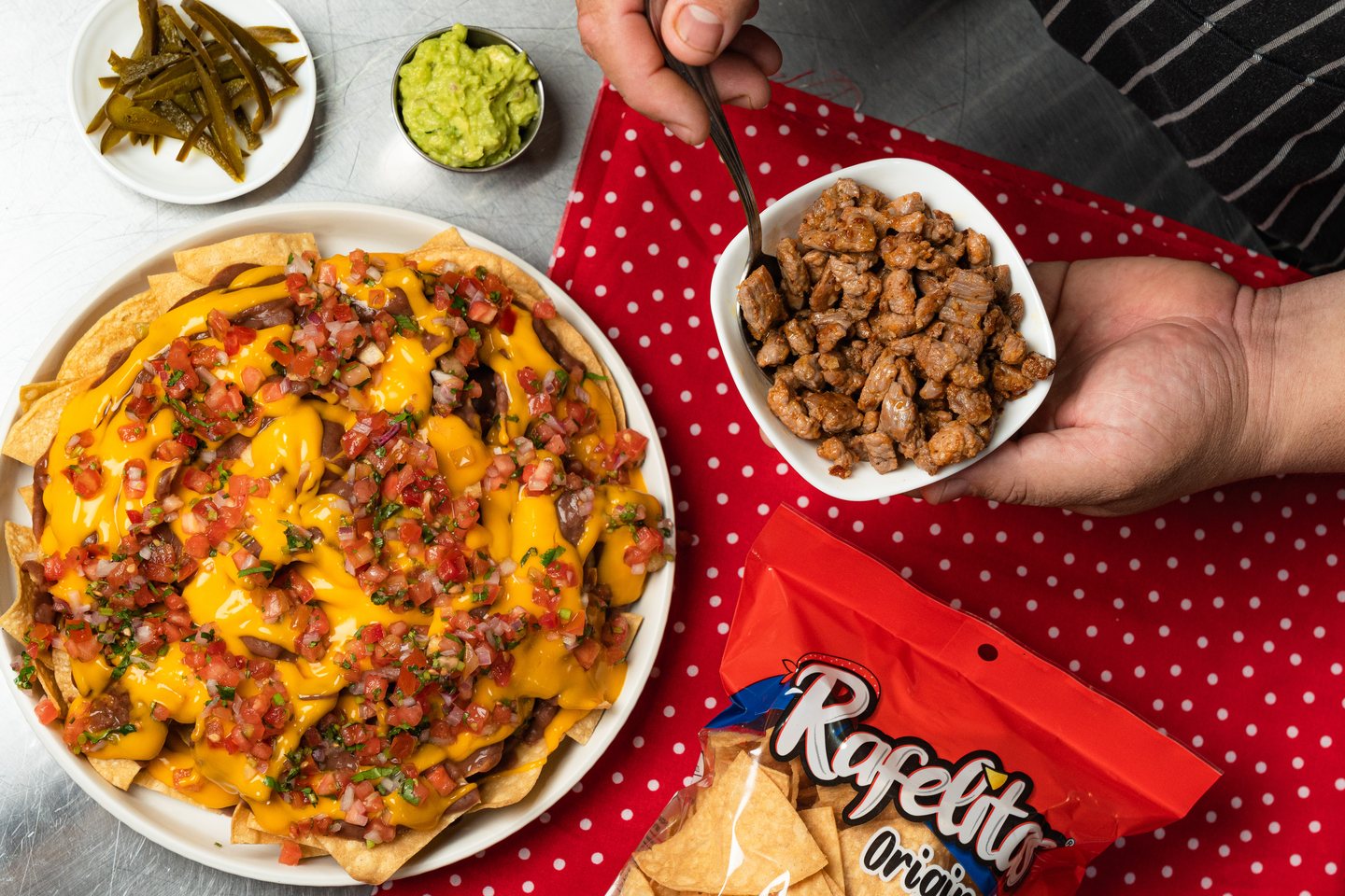 Nachos Tex-Mex con Rafelitas Originales, queso derretido, pico de gallo y carne, junto a una bolsa de Rafelitas